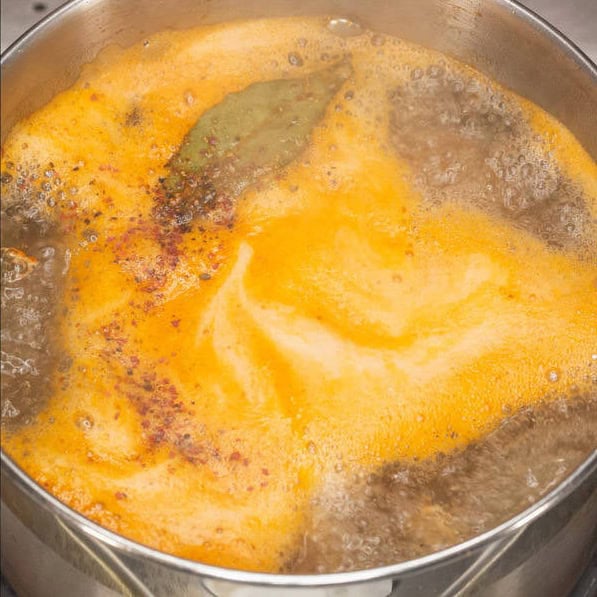 Sauteing the shrimp heads and shells. Boiling the stock in the saucepan.
