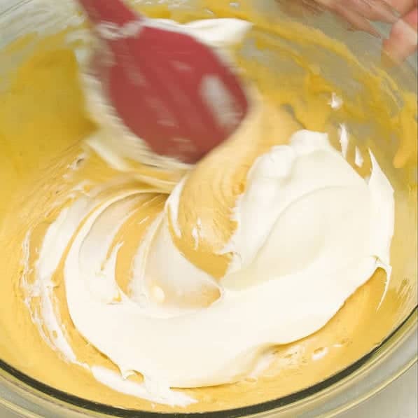 Folding in a portion of the mascarpone mixture to the zabaglione in the bowl. Mixing the remaining mascarpone mixture and the zabaglione in the bowl.