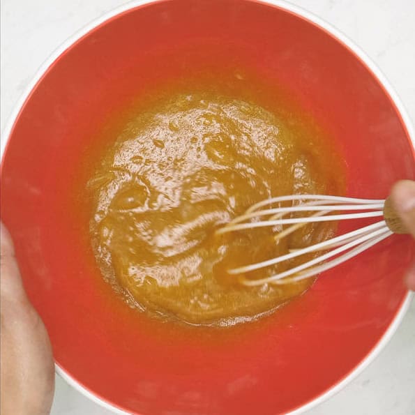 Combining the wet ingredients in a bowl. Mixing the wet ingredients using a whisk.