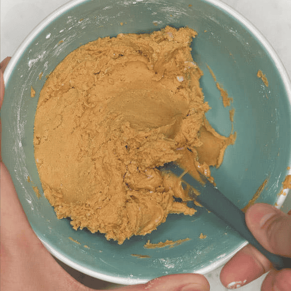 Mixing peanut butter and powdered sugar in a bowl.