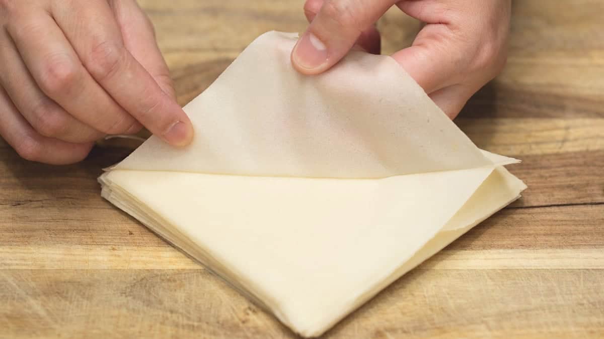 Peeling the spring roll wrappers on a cutting board.