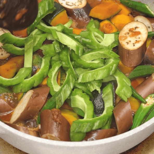 Adding sliced bitter melon to the vegetables.