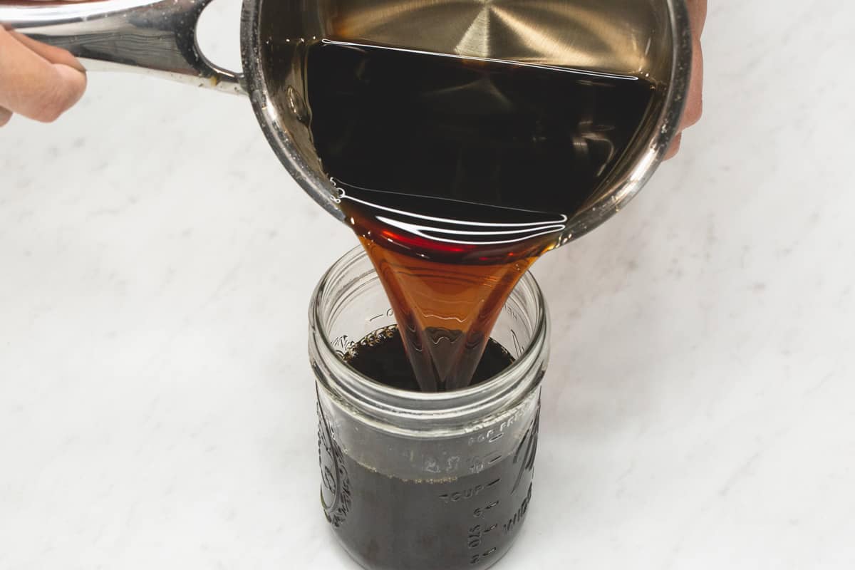 Brown sugar syrup (arnibal) being poured into the mason jar.