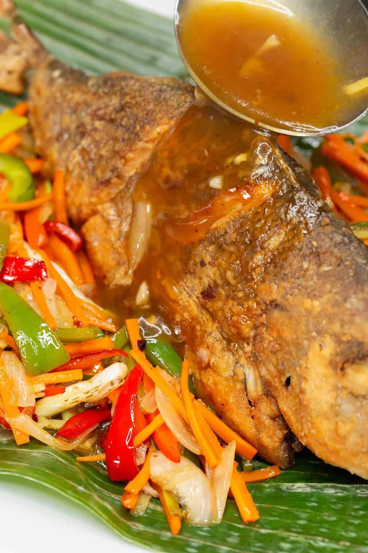 Pouring the sauce over the fish in a platter.