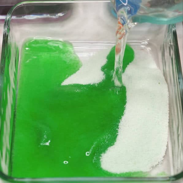 Pouring hot water to dissolve the gelatin powder in the container. Mixing to dissolve the gelatin powder in the liquid.