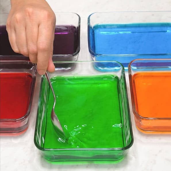 Pouring hot water to dissolve the gelatin powder in the container. Mixing to dissolve the gelatin powder in the liquid.