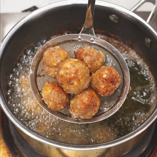 Ground meat mixture in a bowl and straining the fried meatballs in a skimmer over the saucepan.