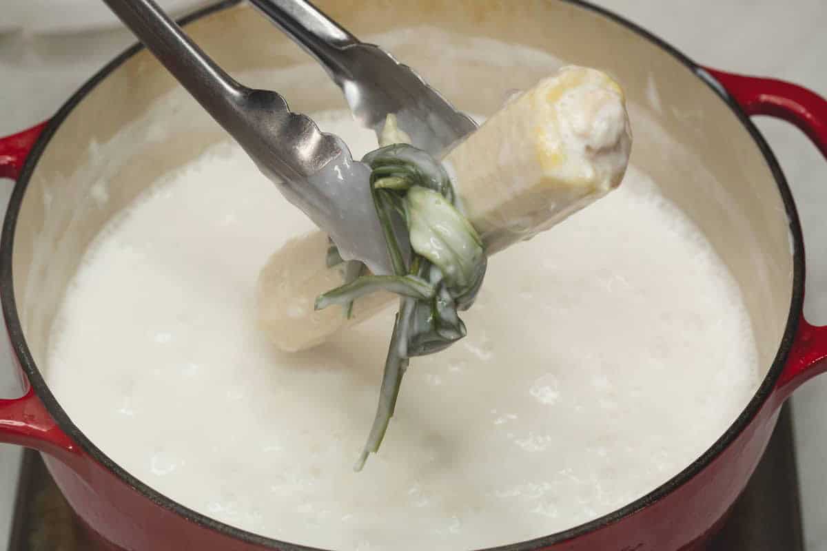Removing the pandan leaves and corn cobs from the mixture. 