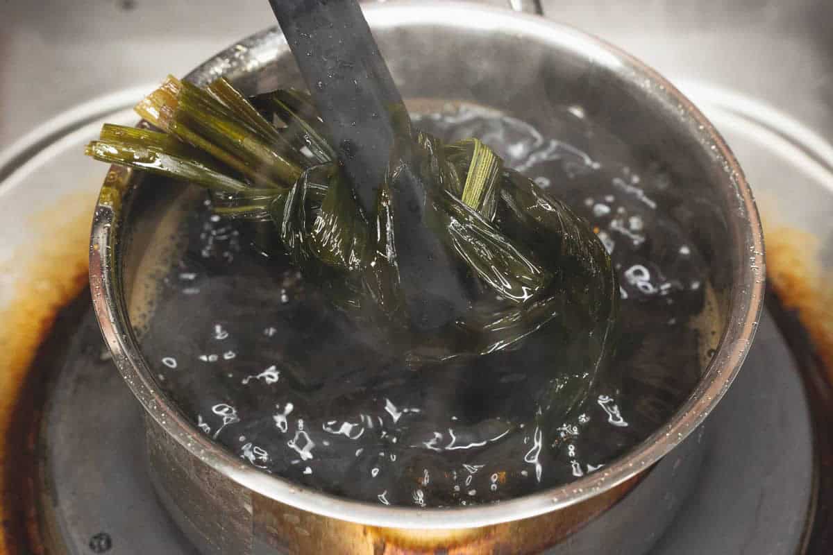 Removing the pandan leaves from the mixture.