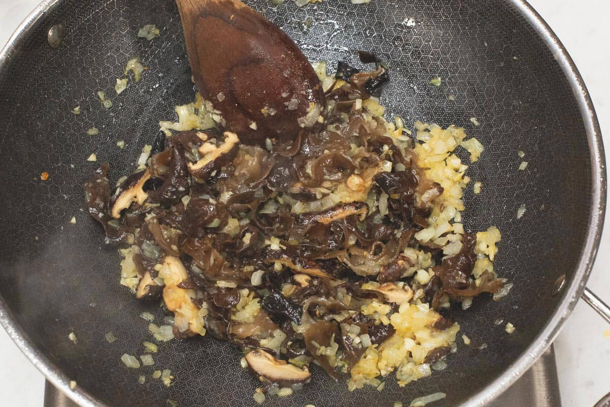 Sauteing the aromatics and mushrooms in a wok.