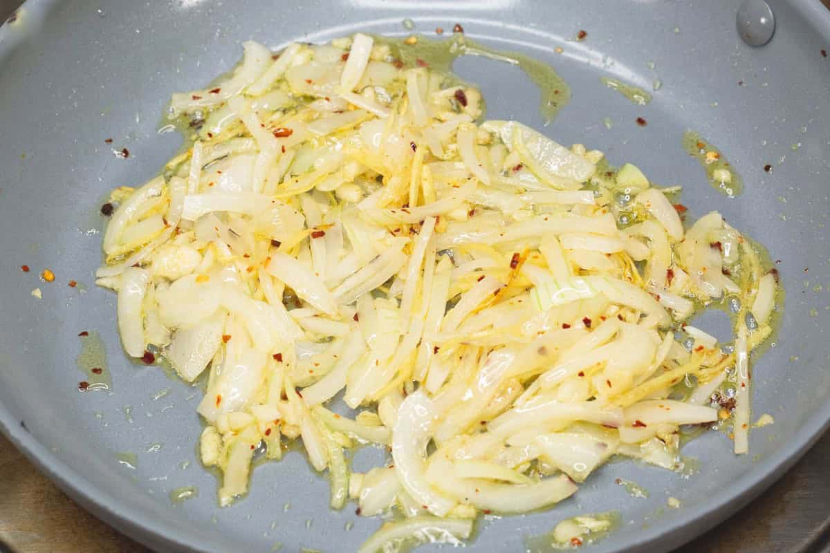 Sauteing aromatics in a skillet.