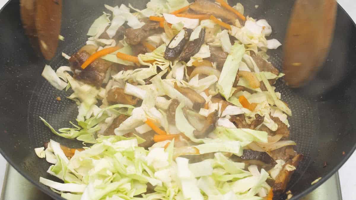 Stir-frying the beef and vegetables in the wok.