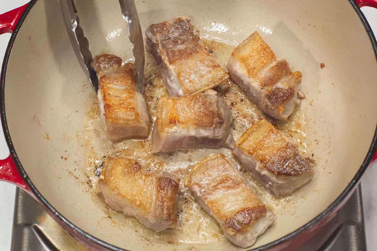 Searing the pork belly in the pot.
