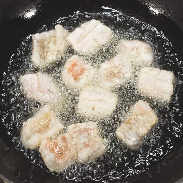 Frying the pieces of fish and draining them on a wire rack.