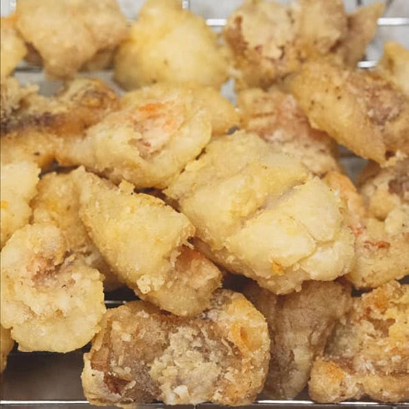 Frying the pieces of fish and draining them on a wire rack.