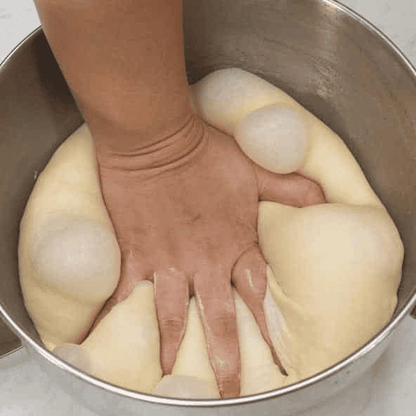 Pressing down the risen Spanish bread dough.