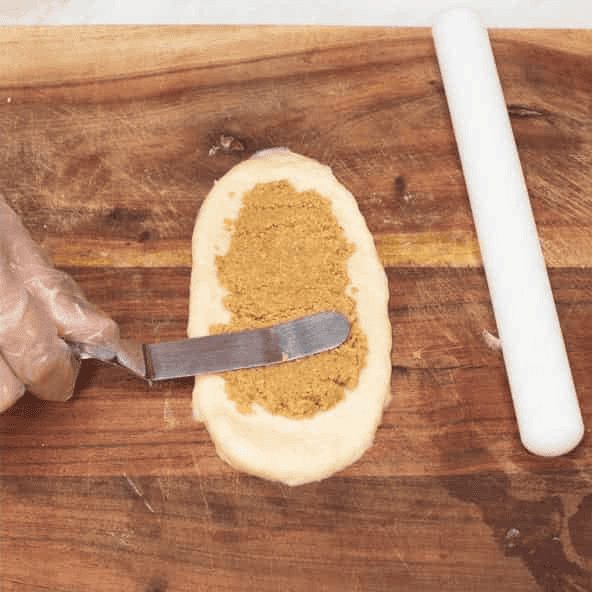Spreading the sweet filling over the flattened dough.