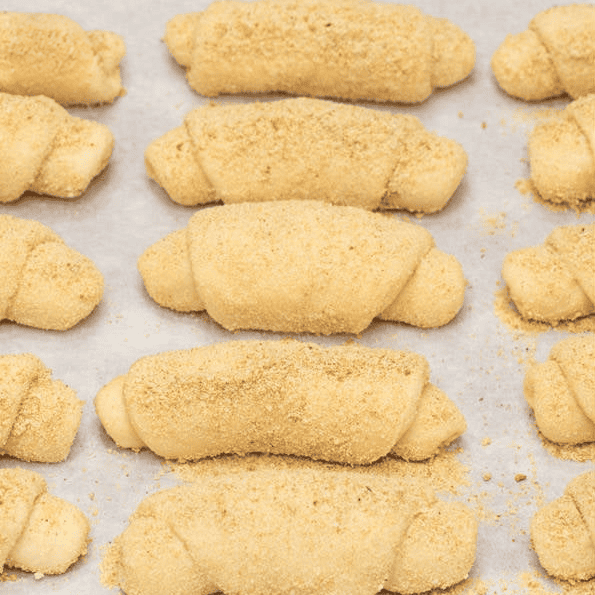 Shaped Spanish bread rolls on a lined baking sheet.