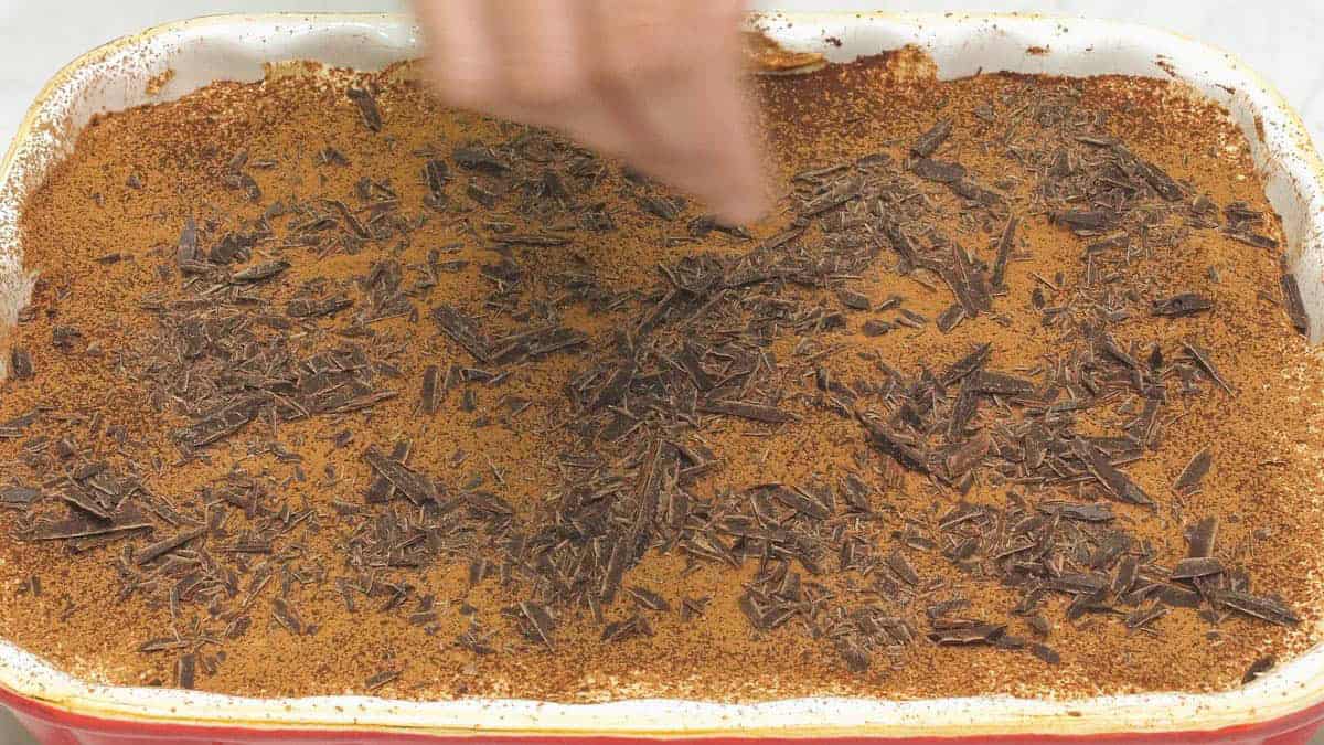 Adding chocolate shavings on top of the Tiramisu with Kahlúa.