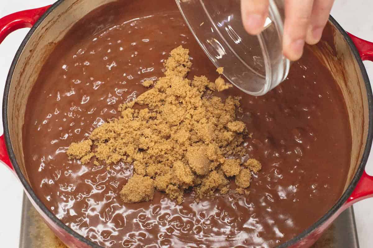 Adding brown sugar to the Champorado in the pot.