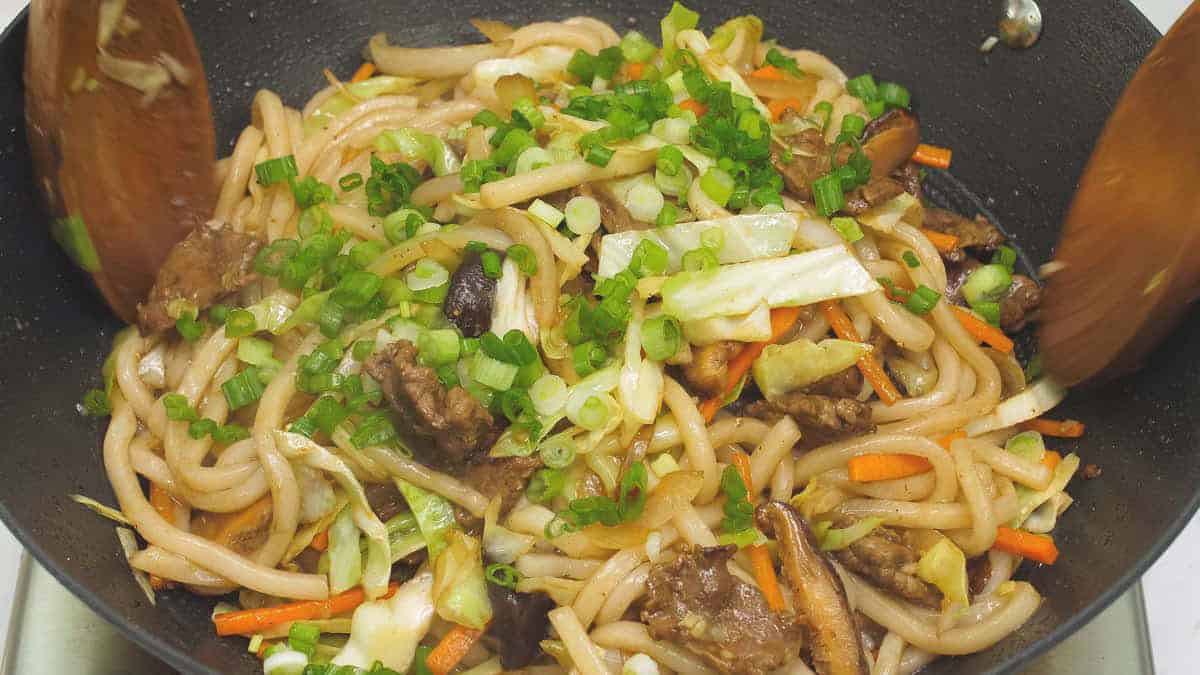 Added scallions to Yaki Udon (Stir-Fried Udon) in the wok.