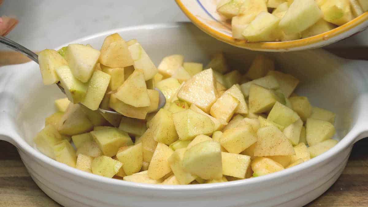 Transferring apple filling to the baking dish with a spoon. 