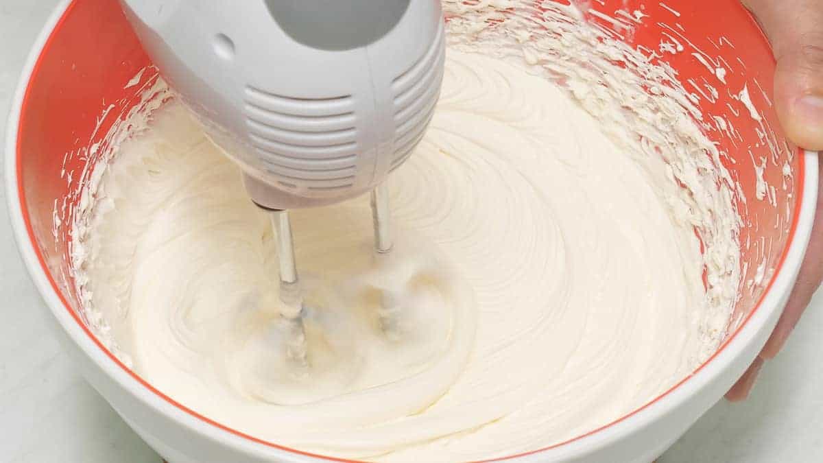 Beating the mixture in the bowl using a hand mixer.